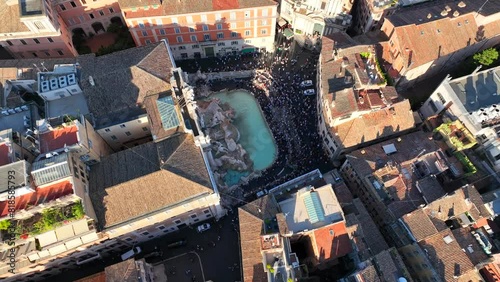 La fontana di Trevi a Roma, gremita di turisti, vista dall'alto.
Ripresa aerea con drone di Fontana di Trevi piena di visitatori in una giornata estiva. photo