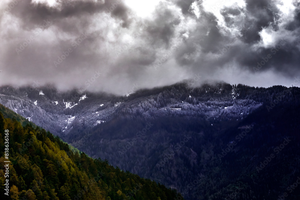 Alpine Peaks with Remnants of Snow and Visible Snow Line in Dark Clouds During Approaching Thunderstorm