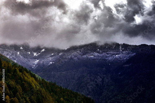 Alpine Peaks with Remnants of Snow and Visible Snow Line in Dark Clouds During Approaching Thunderstorm