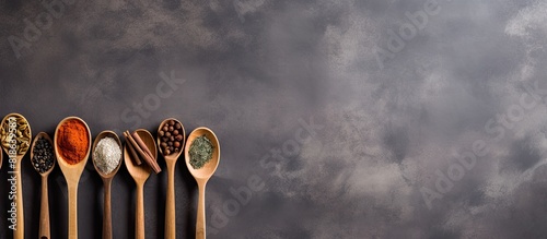 A gray background with copy space image showcases a variety of wooden spoons adorned with various spices