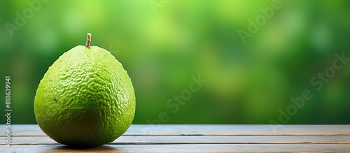 A fresh Cupuacu fruit is seen up close on a green painted wooden table with ample space for copying images photo