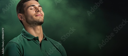 A young attractive man in a polo shirt is seen relaxing in the copy space image