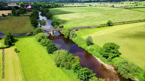 Aerial drone footage of the beautiful village and civil parish of Pool in Wharfedale in West Yorkshire England showing the River Wharfe on a sunny day in the summer time photo