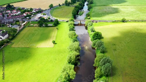 Aerial drone footage of the beautiful village and civil parish of Pool in Wharfedale in West Yorkshire England showing the River Wharfe on a sunny day in the summer time photo