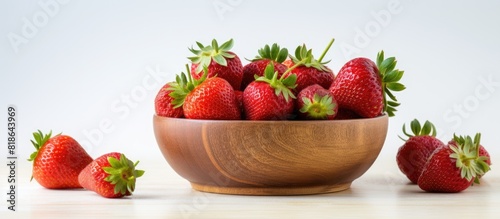 A copy space image of fresh organic strawberries displayed in a wooden bowl resting on top of a white table