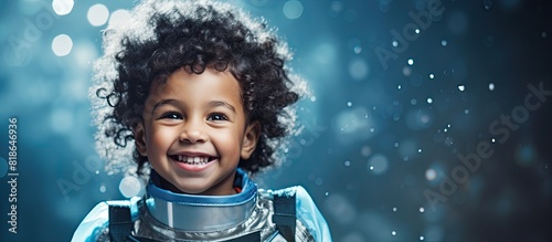 Copy space image of a joyful mixed race boy in a space suit pretending to be an astronaut on a blue backdrop adorned with handcrafted white stars showcasing his imaginative and creative side during hi