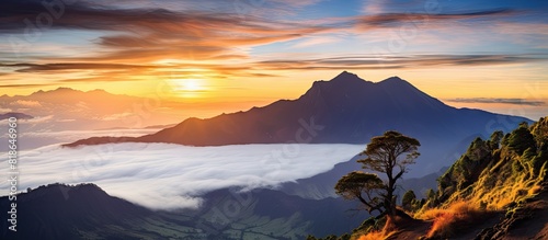 A breathtaking sunset on Mount Rinjani s hill overlooking a picturesque valley with a copy space image of clouds engulfing the cliff photo