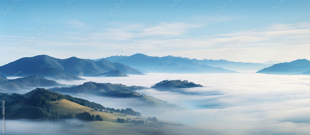 The misty fog in the sky creates a serene and tranquil atmosphere over the sea landscape of rolling hills providing a captivating natural background for any copy space image