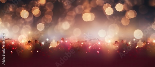 Copy space image of a dark burgundy red Christmas blur background with glowing lights from the garland and decorative ornaments on the tree