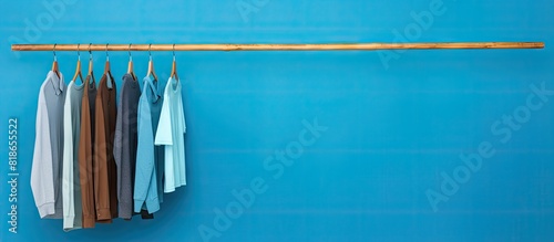 A humorous and confident man playfully poses on a wooden clothes hanger against a vibrant blue backdrop leaving ample copy space in the image 138 chars