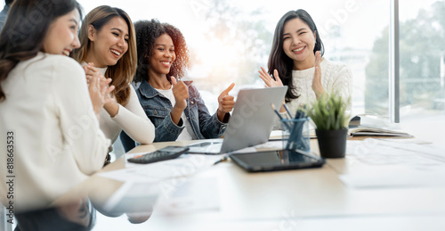 Happy businesspeople laughing while collaborating on a new project in an office. Group of diverse businesspeople using a laptop while working together in office