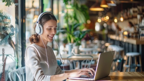 Smiling woman wearing headphones and working on a laptop in a cozy café, perfect for themes of remote work, productivity, and casual workspaces.