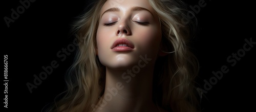 Copy space image of a blonde girl young and beautiful with closed eyes portraying a melancholic expression on a dark backdrop