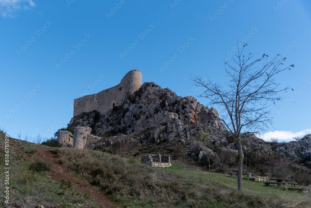Fototapeta premium Impressive view of the medieval castle of Los Roja built on a hill surrounded by rocks in the province of Burgos at sunset
