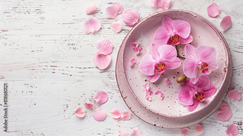 Plate with beautiful orchid flowers on light wooden background