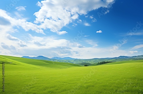 Green grassy hills with blue sky and mountains landscape background