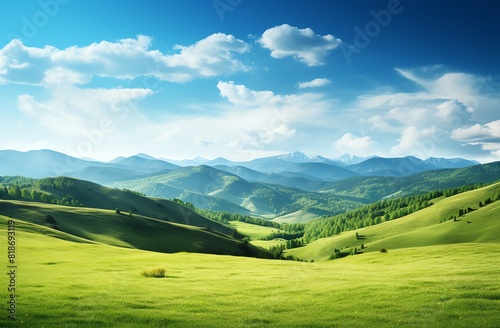 Green grassy hills with blue sky and mountains landscape background