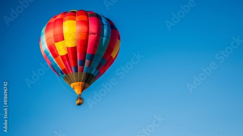 A colorful hot air balloon drifting peacefully across a clear blue sky, offering a serene and scenic mode of aerial transport. © Atif