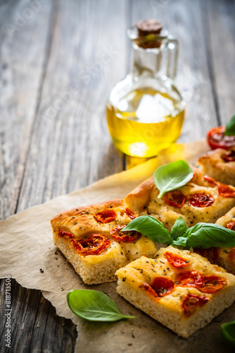 Focaccia - baked sandwich with tomatoes and basil leaves on wooden table