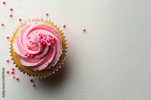 An overhead shot captures the vibrant pink icing on a cheerful cupcake against a white backdrop
