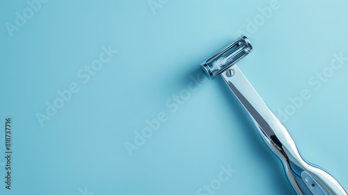 A silver metal safety razor on a blue background. The razor has a single blade and a handle with a textured grip. photo