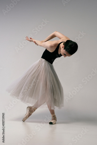 ballerina in a bodysuit and a white skirt improvises classical and modern choreography in a photo studio photo