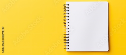 Top down view of a yellow background with a spiral notepad featuring white pages and ample copy space for adding images or text photo
