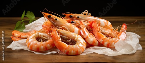 Raw shrimp complete with tails and shells arranged on a wooden table and wrapped in butcher s paper Copy space image photo