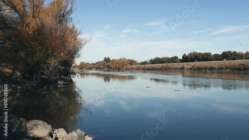 Flowing tranquil water of Sacramento River and the levee in the fall in California, USA