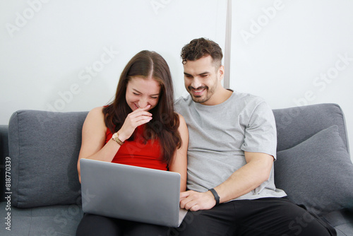 Smiling Caucasian Couple love relaxing for shopping online in social media with laptop together on sofa in living room. Technology and lifestyle on holiday of family Concept © cocorattanakorn