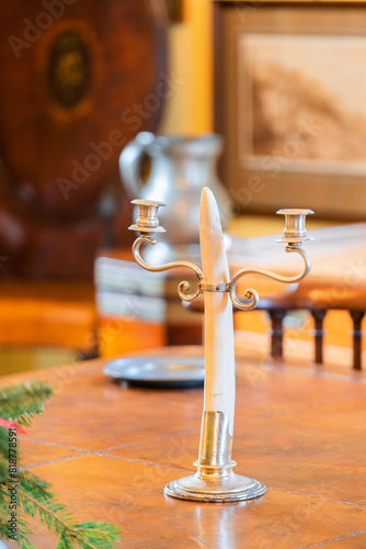 close-up of an antique candle holder on a wooden table  surrounded by silverware and rustic decor
