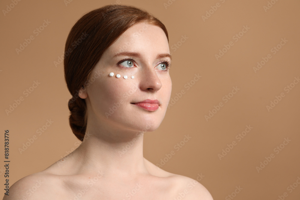 Beautiful woman with freckles and cream on her face against beige background. Space for text