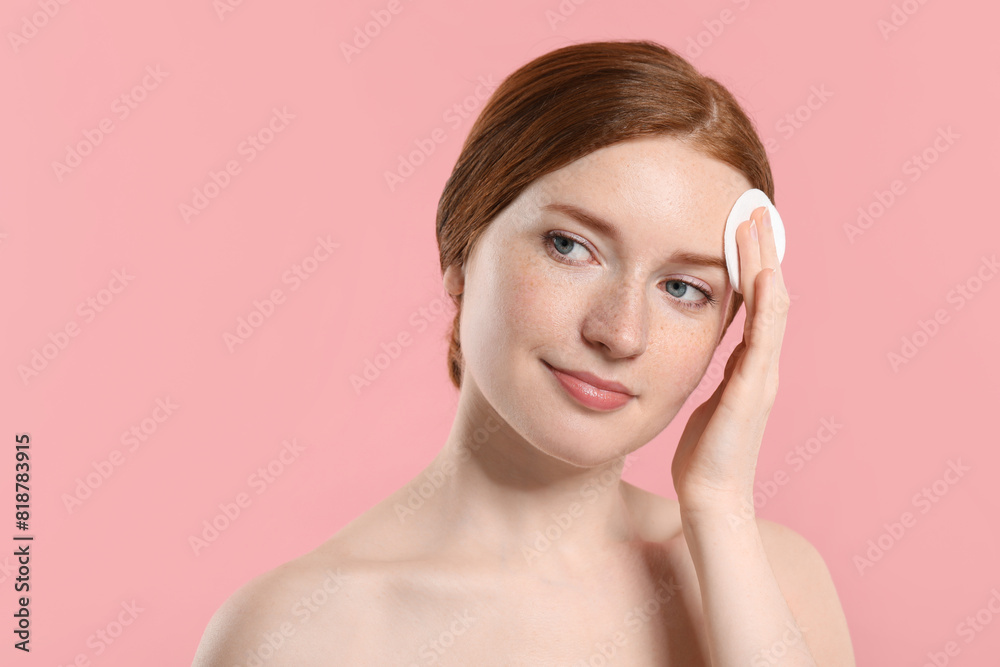 Beautiful woman with freckles wiping face on pink background Beautiful woman with freckles wiping face on pink background
