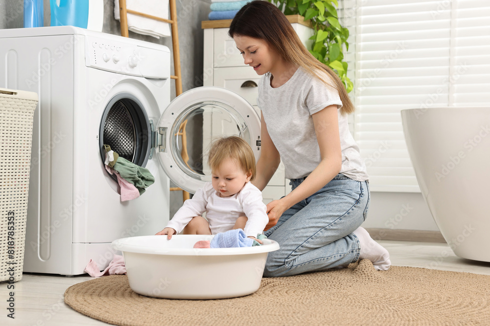 Mother with her daughter washing baby clothes in bathroom Mother with her daughter washing baby clothes in bathroom