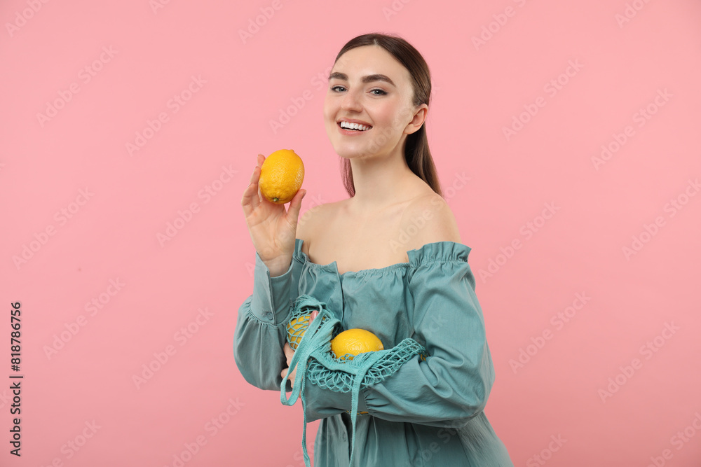 Woman with string bag of fresh lemons on pink background Woman with string bag of fresh lemons on pink background