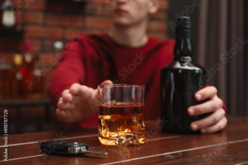 Sticker Man reaching for alcoholic drink at table with car keys, closeup