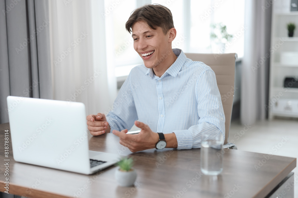 Man using video chat during webinar at wooden table in office Man using video chat during webinar at wooden table in office