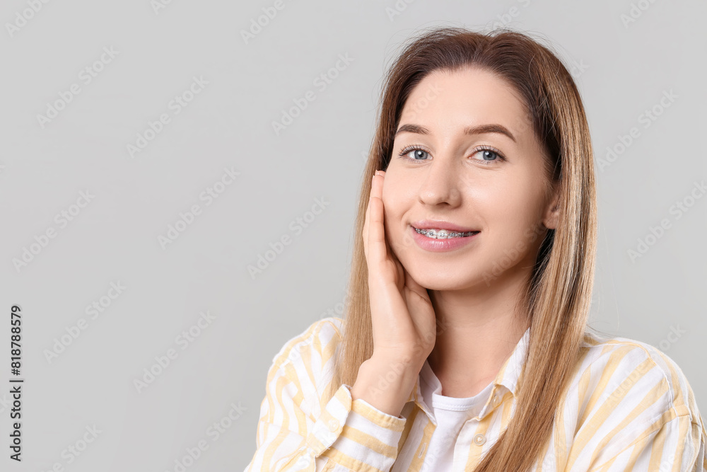 Portrait of smiling woman with dental braces on grey background. Space for text Portrait of smiling woman with dental braces on grey background. Space for text