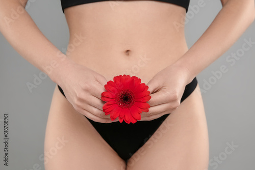 Gynecology. Woman in underwear with gerbera flower on grey background, closeup