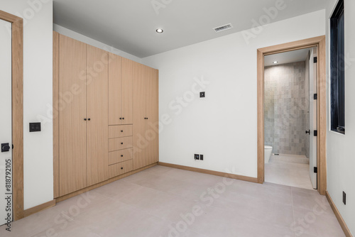 a bedroom with white walls and light wooden closets and a toilet