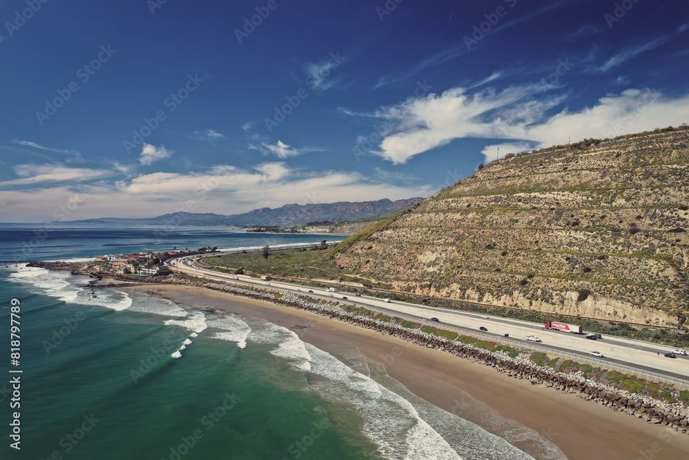 an aerial view of a beach near the ocean with cars driving along the shore an aerial view of a beach near the ocean with cars driving along the shore