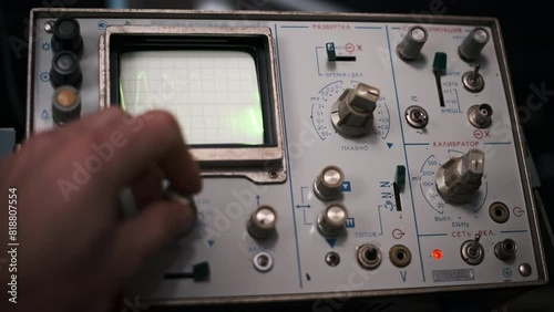 A vintage oscilloscope displays a vibrant green waveform on its screen. The footage highlights the retro aesthetic of analog technology and the visual representation of electronic signals. photo