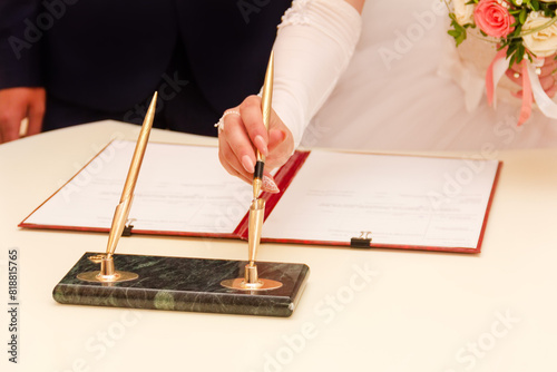 the hand of a young bride takes a pen to sign a marriage contract close-up