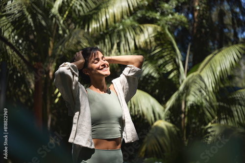 Bild auf Leinwand Happy relaxed young Hispanic woman enjoying summer sunny day with eyes closed feeling no stress, peace of mind, mental balance relaxing standing in green nature park among tropical trees