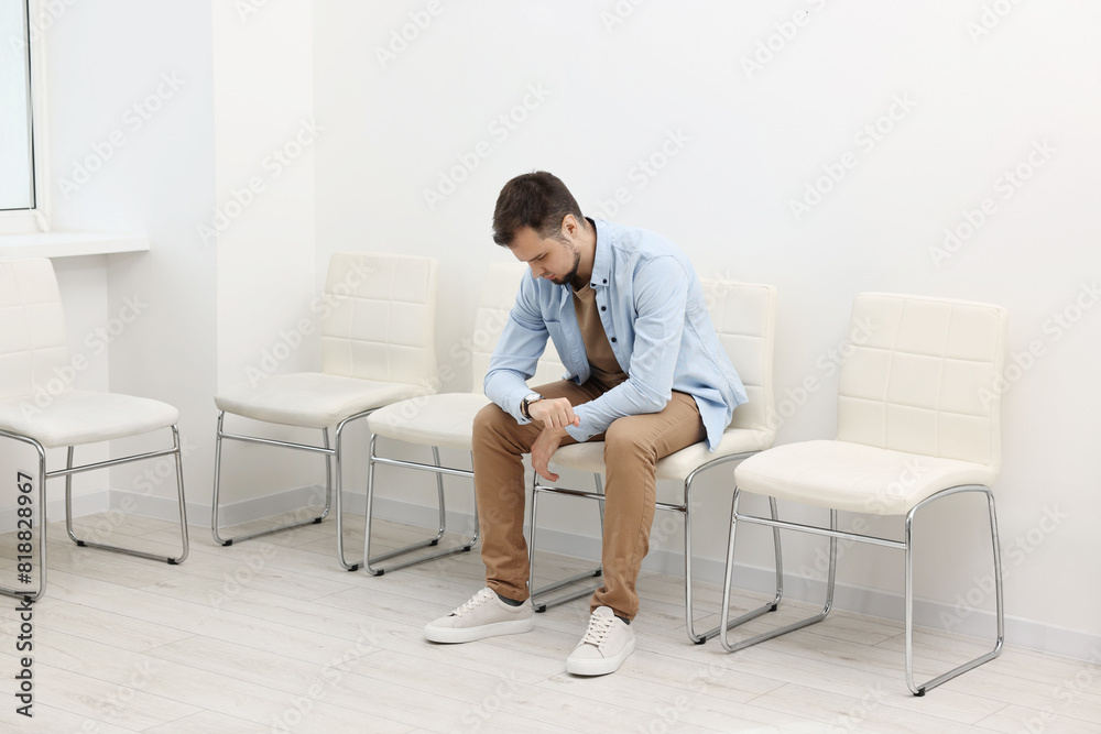 Man looking at wrist watch and waiting for job interview indoors Man looking at wrist watch and waiting for job interview indoors