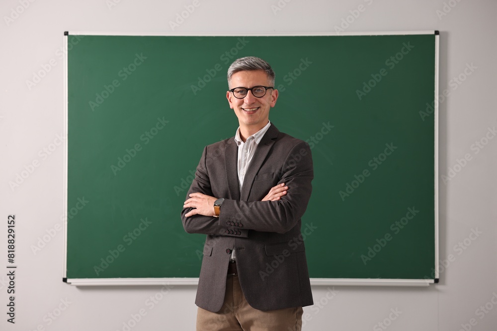Teacher in glasses near chalkboard in classroom Teacher in glasses near chalkboard in classroom
