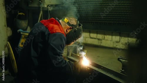 Welder in action, welding process, metalworks with sparks illuminating the work area in workshop. 