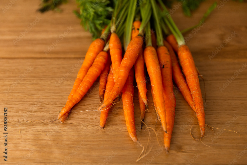 bunch of small orange carrots fanned out on a wooden table bunch of small orange carrots fanned out on a wooden table