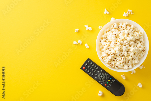 Enjoy movie night at home with app on TV. Top view of savory snack, and remote for streaming. Yellow backdrop with space for text or advertising