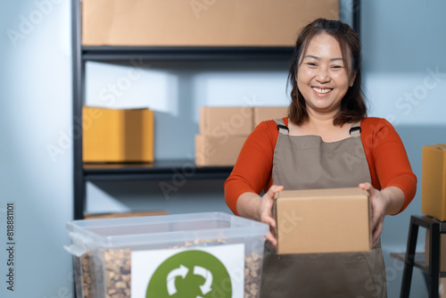 A smiling woman in an apron packs a cardboard box using eco-friendly materials in a home-based business highlighting the sustainable practices of a small business